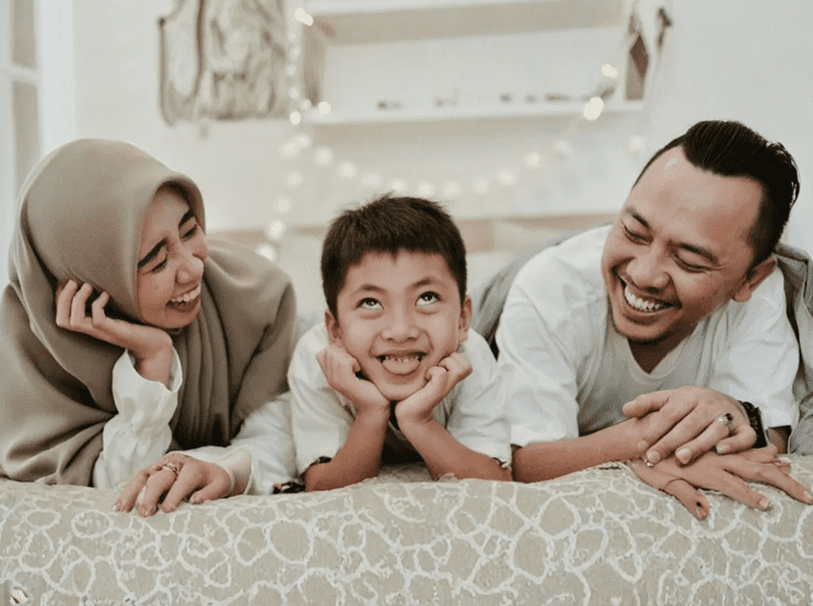 Happy family laughing together on bed.